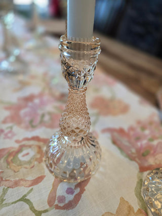Decorative coral glass candle holder with intricate design on a floral linen table runner.